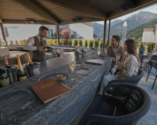 Alt: Bancone in pietra de La Rotonda Champagnerie con bottiglie di champagne, sommelier al servizio e ospiti con vista sulle Orobie al Collina Luxury Relais di Clusone