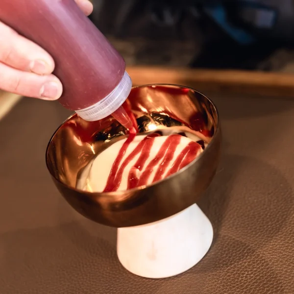 Frozen yogurt con salsa di fragole in coppa di rame su tavolo in legno al Beides Restaurant