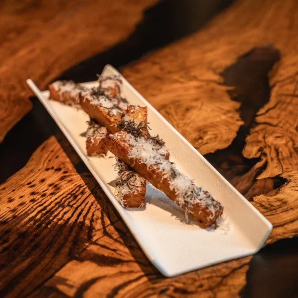 Patatine fritte con Parmigiano Reggiano Vacche Rosse e tartufo nero su piatto bianco al Beides Restaurant