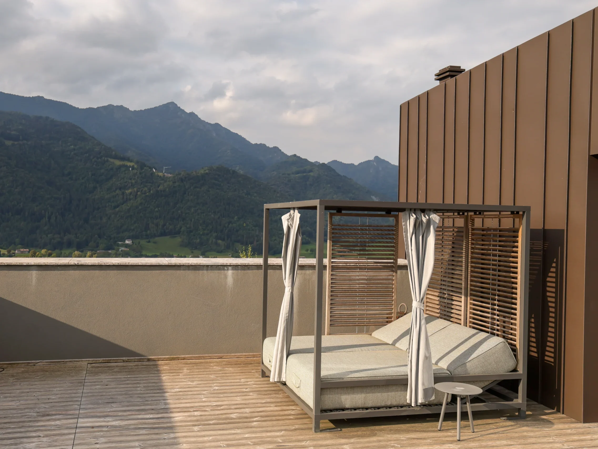 Terrazza Penthouse con daybed a baldacchino su pedana in legno e vista panoramica sulle montagne della Valseriana