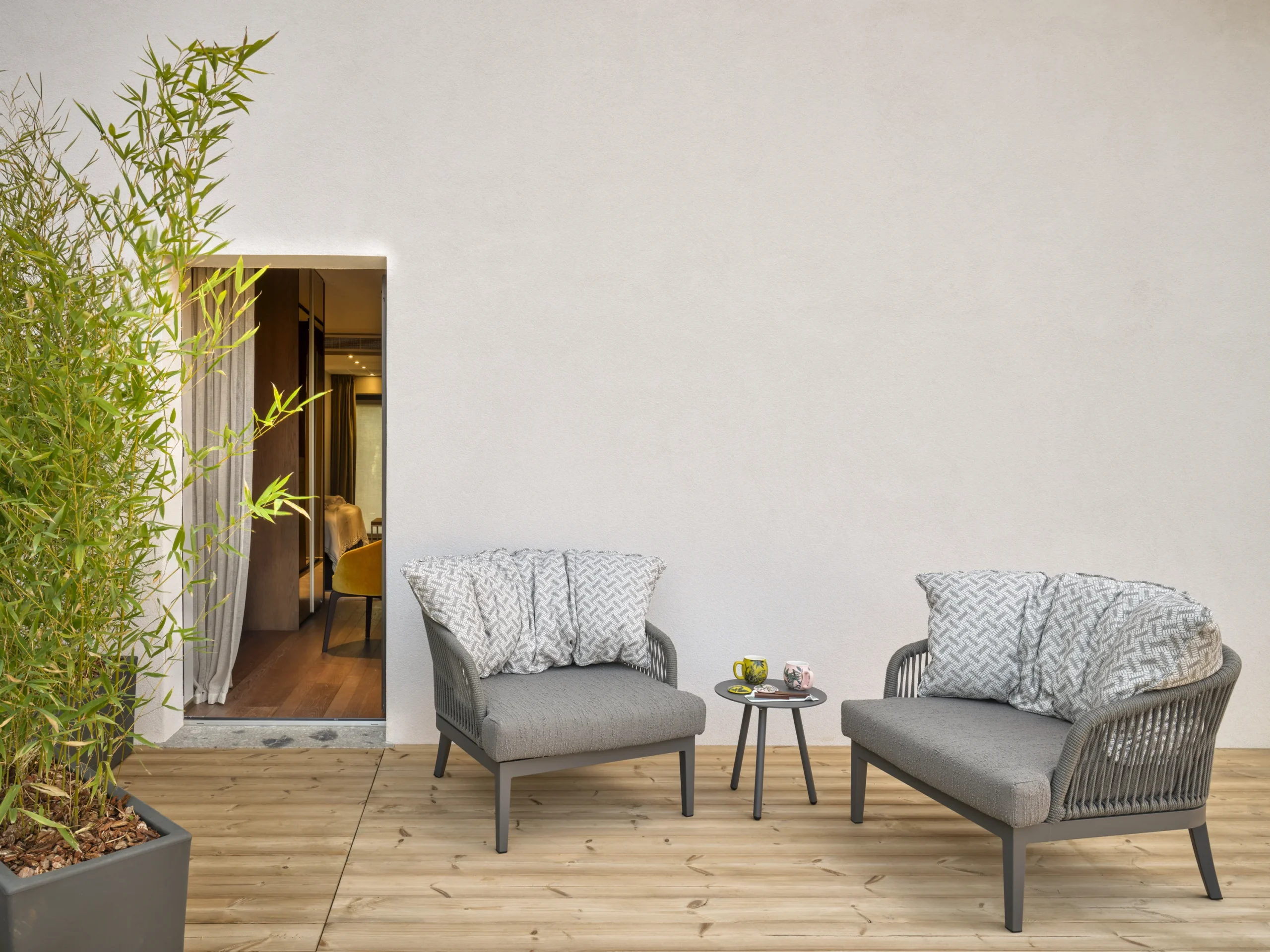 Terrazza privata Signature Suite con due poltroncine grigie, tavolino rotondo, bambù e accesso alla camera